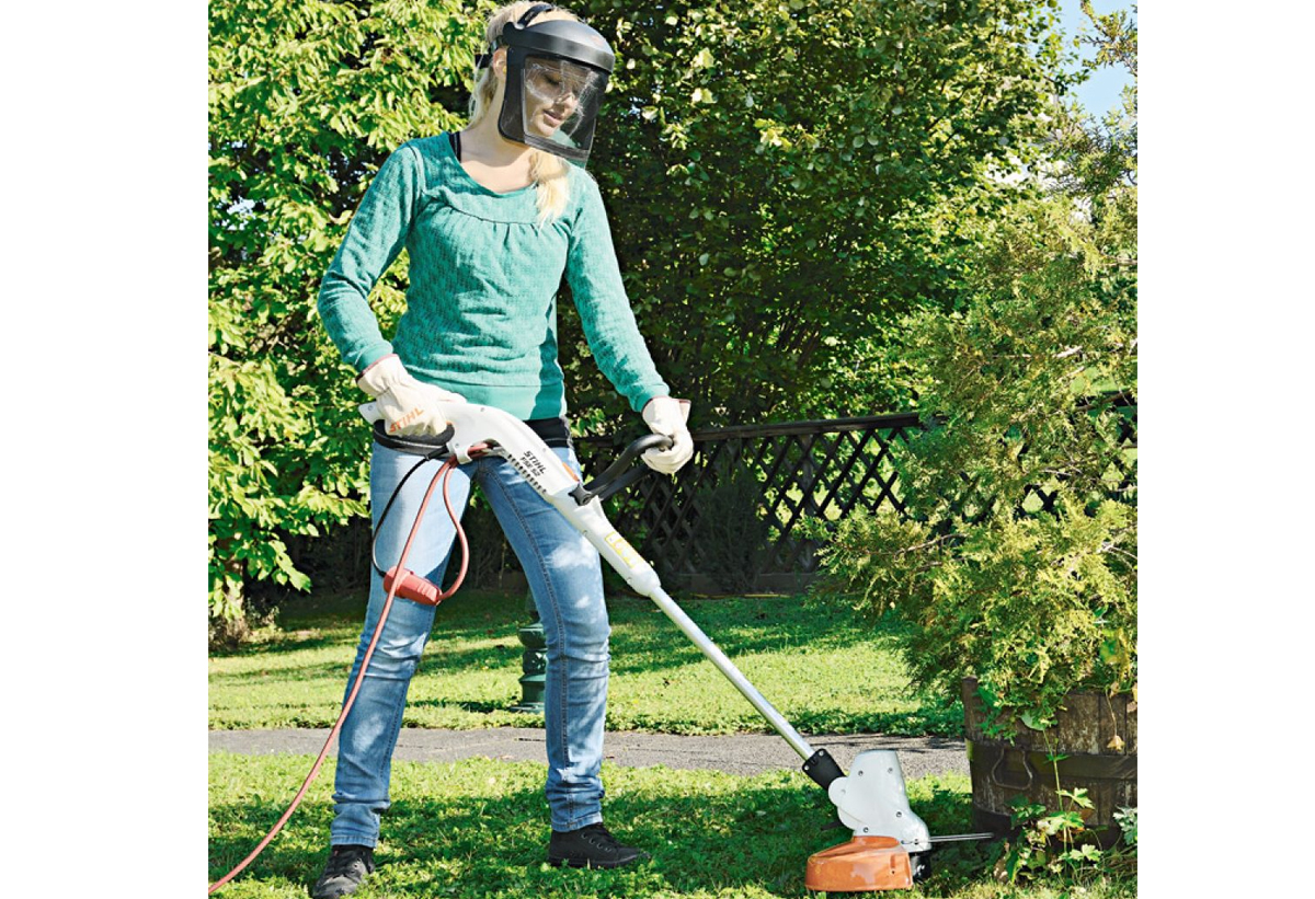 Μία γυναίκα κουρεύει τον κήπο της.